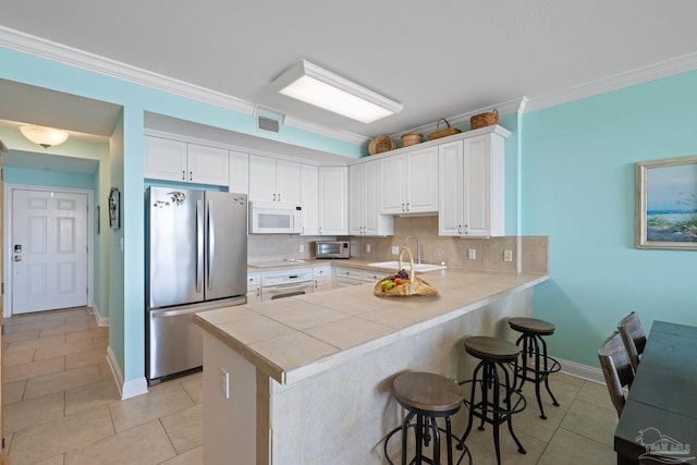 4050 Indigo Dr Unit 102, Pensacola, FL 32507 - kitchen featuring white appliances, a peninsula, a kitchen breakfast bar, crown molding, and light tile patterned flooring