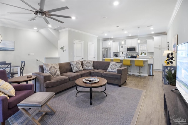 living room with ornamental molding, ceiling fan, and light hardwood / wood-style flooring