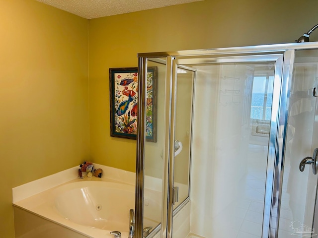 bathroom featuring a shower stall, a tub with jets, and a textured ceiling