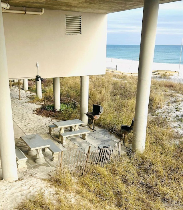 view of patio / terrace featuring a view of the beach, a water view, and visible vents