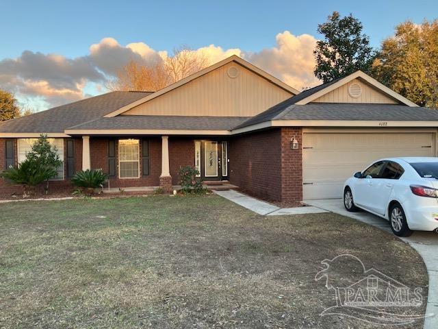 single story home featuring driveway, a front lawn, an attached garage, and brick siding