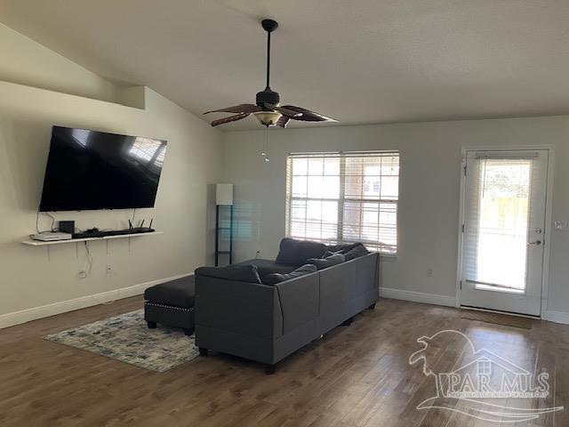 living area with vaulted ceiling, ceiling fan, wood finished floors, and baseboards