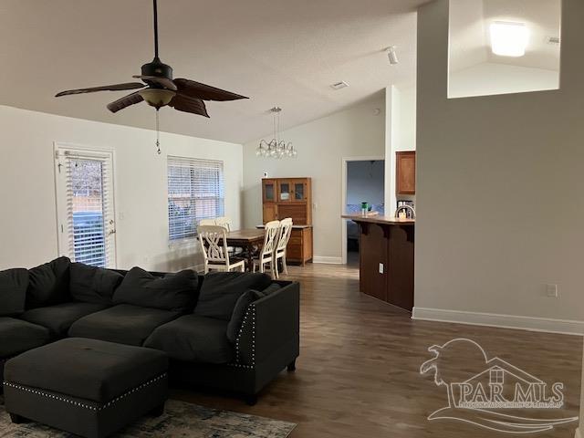 living area featuring lofted ceiling, ceiling fan, baseboards, and dark wood-type flooring