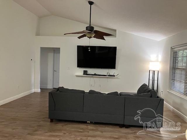 living area featuring baseboards, a ceiling fan, vaulted ceiling, and wood finished floors