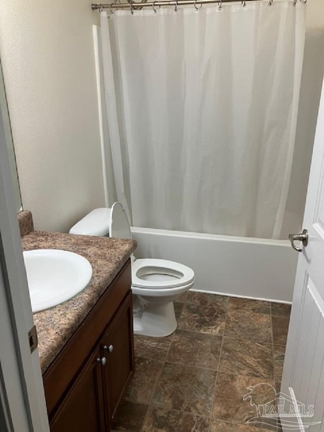 bathroom with toilet, stone finish floor, and vanity