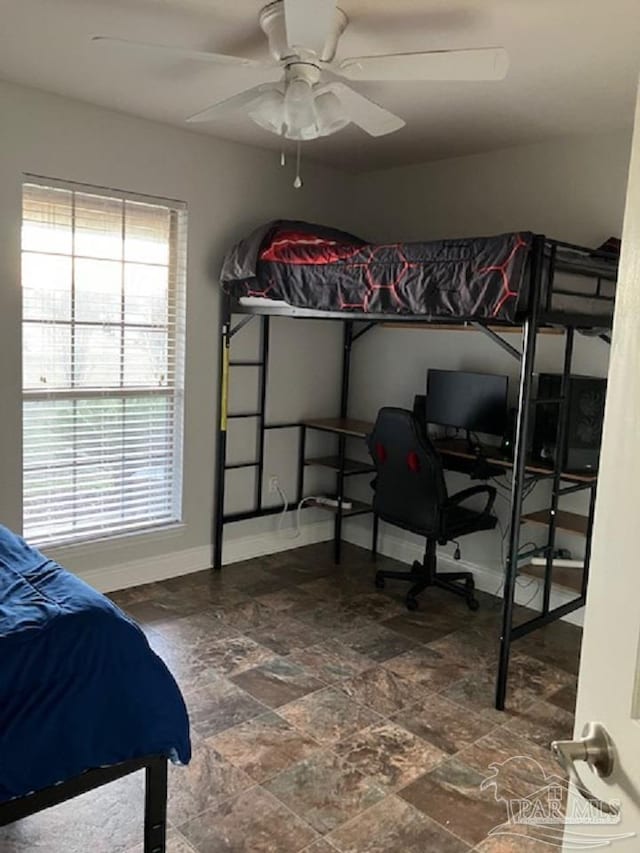 bedroom with stone finish flooring, multiple windows, a ceiling fan, and baseboards