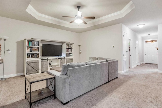 living room with ceiling fan, a raised ceiling, crown molding, and carpet flooring