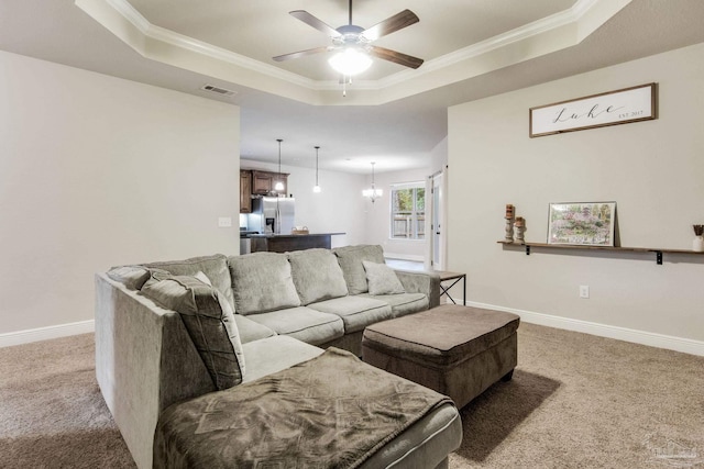 carpeted living room with ceiling fan with notable chandelier, crown molding, and a raised ceiling