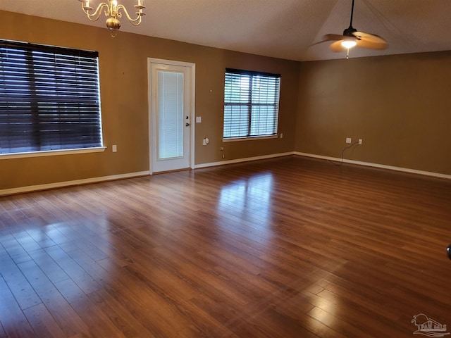 unfurnished room with a textured ceiling, ceiling fan with notable chandelier, and dark wood-type flooring