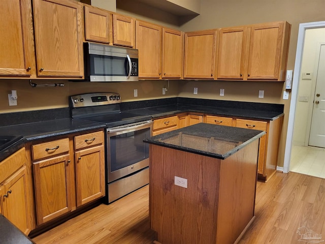 kitchen featuring dark stone countertops, a center island, light wood-type flooring, and appliances with stainless steel finishes