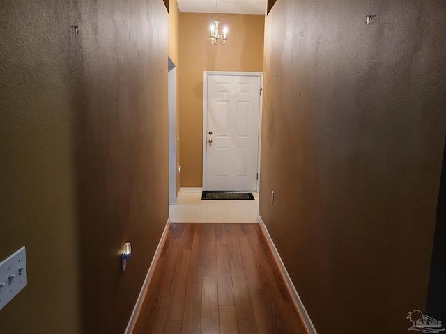 corridor with a chandelier and light wood-type flooring