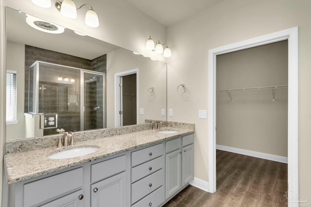 bathroom featuring dual vanity, walk in shower, and hardwood / wood-style flooring