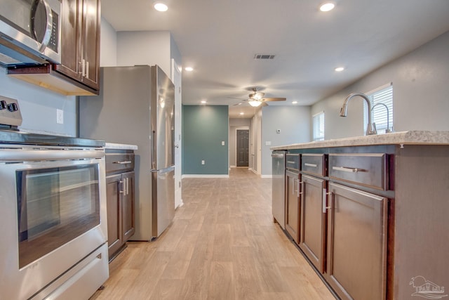 kitchen with ceiling fan, sink, stainless steel appliances, and light hardwood / wood-style flooring