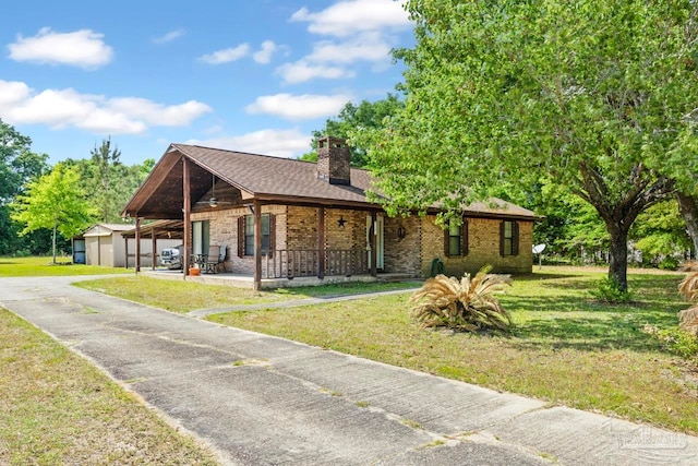 view of front facade with an outbuilding, a front lawn, driveway, a chimney, and covered porch