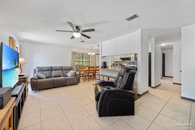 living area featuring a textured ceiling, visible vents, light tile patterned floors, and ceiling fan with notable chandelier