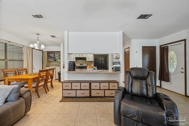 living room featuring a chandelier, a textured ceiling, visible vents, and light tile patterned floors