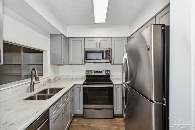 kitchen with a textured ceiling, stainless steel appliances, sink, and gray cabinetry