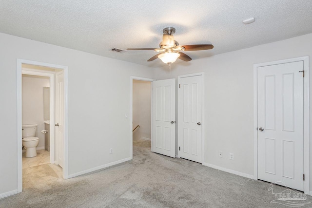 unfurnished bedroom with a textured ceiling, light colored carpet, ceiling fan, and connected bathroom