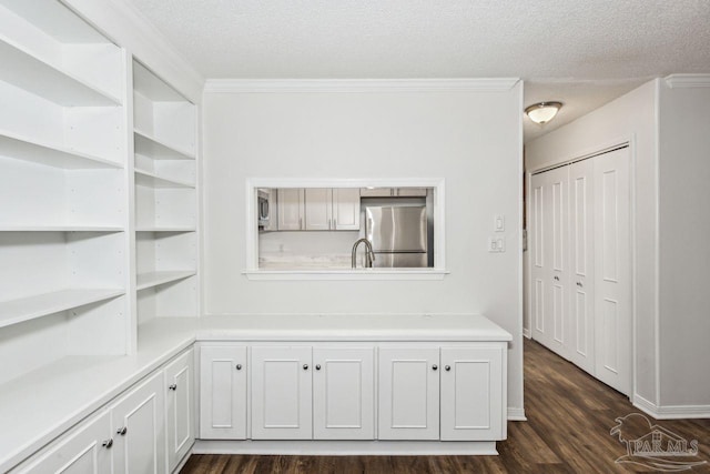 interior space with ornamental molding, stainless steel fridge, a textured ceiling, and dark wood-type flooring