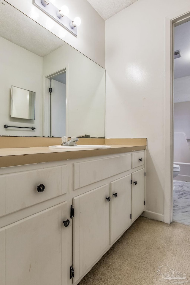 bathroom featuring toilet, a textured ceiling, and vanity