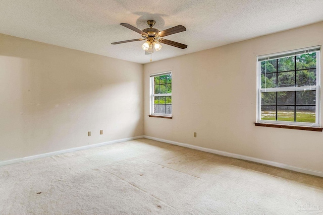 empty room featuring ceiling fan, a wealth of natural light, and light carpet