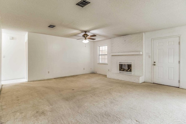 unfurnished living room with ceiling fan, light colored carpet, a textured ceiling, and a fireplace