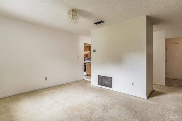 unfurnished room featuring a textured ceiling and light carpet