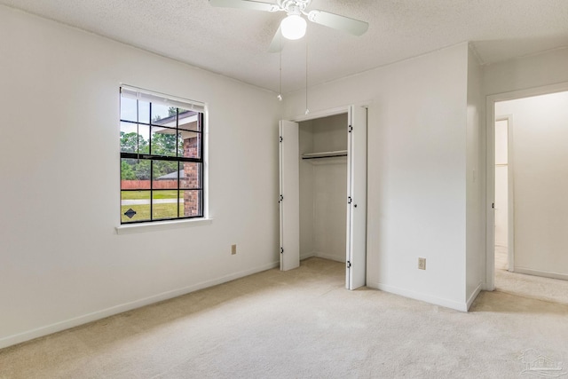 unfurnished bedroom featuring ceiling fan, light carpet, a textured ceiling, and a closet