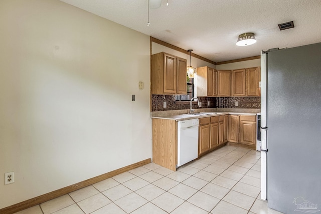 kitchen with sink, dishwasher, light tile patterned floors, pendant lighting, and refrigerator