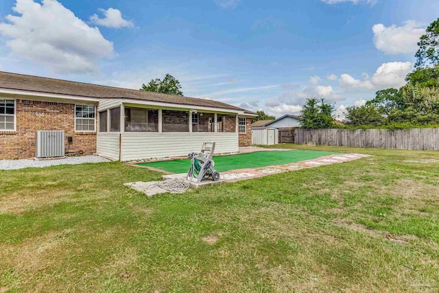 view of yard with a sunroom, a storage shed, and central AC