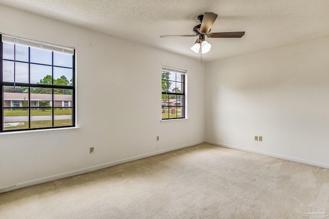 empty room with ceiling fan, light carpet, and a textured ceiling