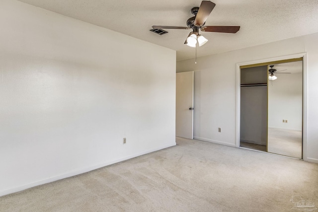 unfurnished bedroom featuring ceiling fan, a closet, a textured ceiling, and light colored carpet