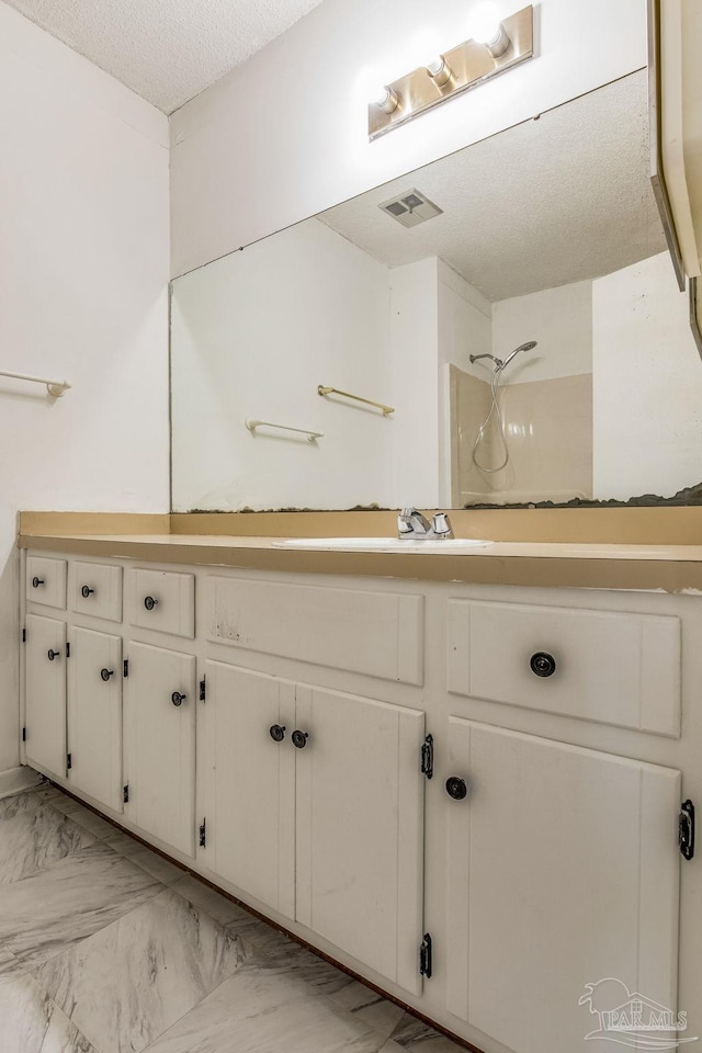 bathroom with tile patterned flooring, walk in shower, vanity, and a textured ceiling