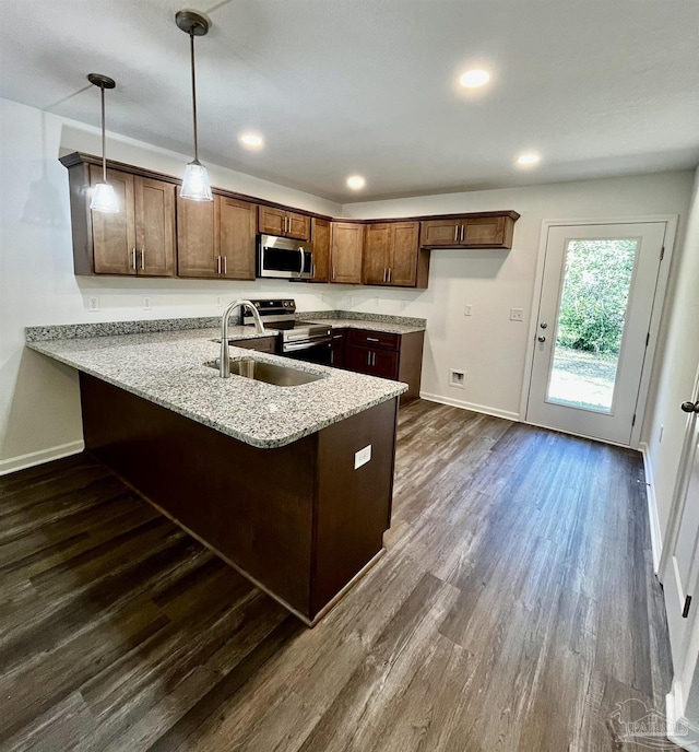 kitchen with dark wood-style floors, light stone countertops, a peninsula, a sink, and stainless steel appliances