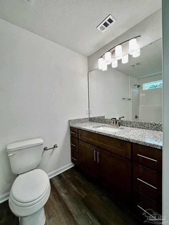 full bathroom featuring a textured ceiling, wood finished floors, visible vents, walk in shower, and toilet