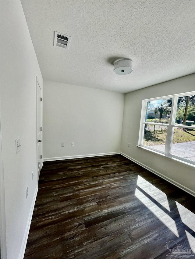 unfurnished room featuring visible vents, baseboards, a textured ceiling, and wood finished floors