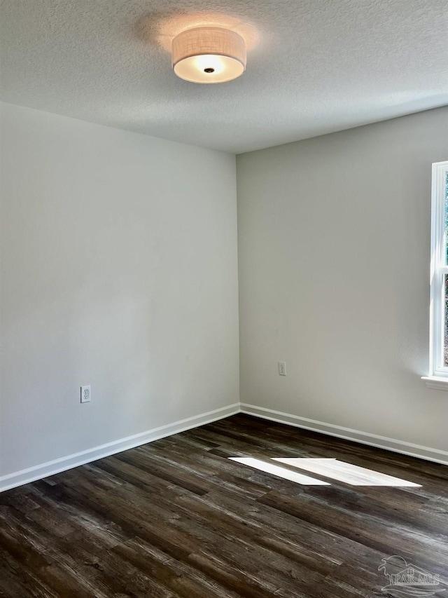 empty room featuring dark wood finished floors, a textured ceiling, and baseboards