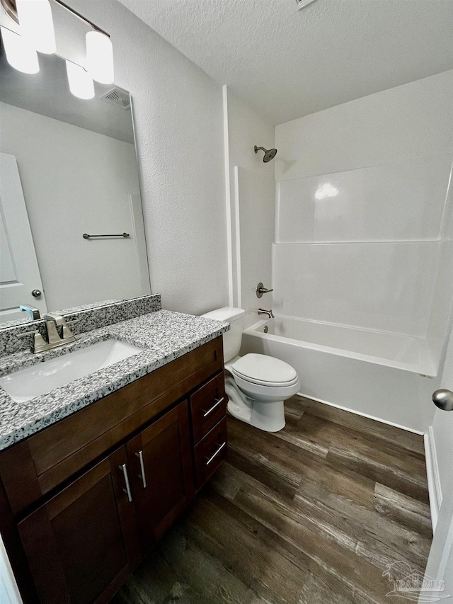 full bathroom with visible vents, toilet, vanity, wood finished floors, and a textured ceiling