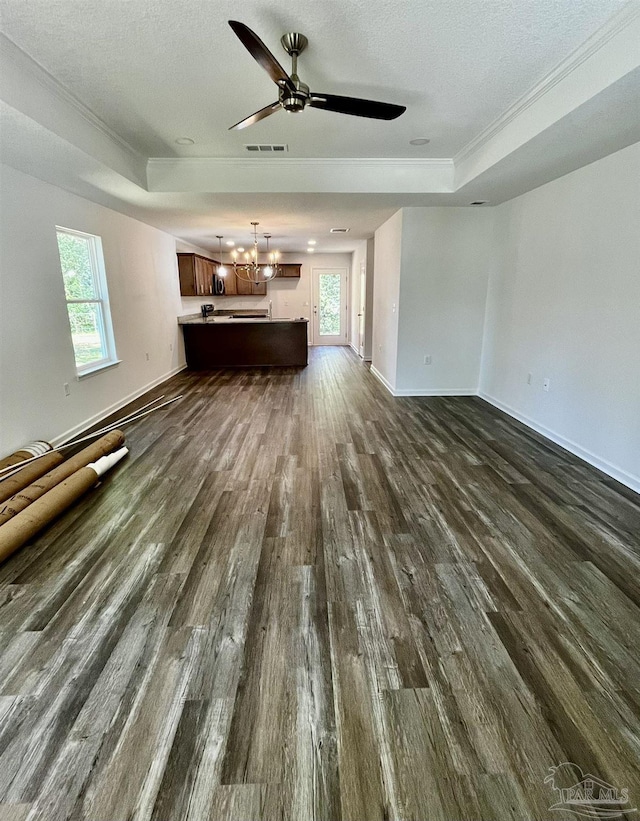 unfurnished living room featuring dark wood finished floors, visible vents, a healthy amount of sunlight, and a tray ceiling