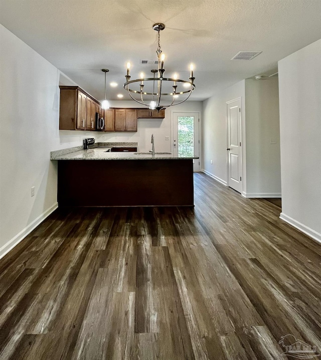 kitchen with stainless steel microwave, a peninsula, light stone countertops, stove, and dark wood-style flooring