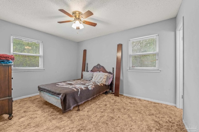 bedroom with multiple windows, ceiling fan, light carpet, and a textured ceiling