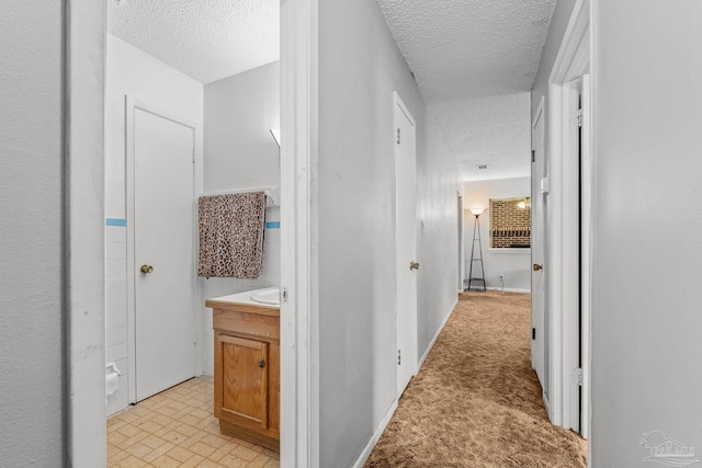 corridor featuring light carpet and a textured ceiling