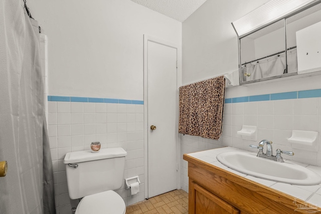 bathroom with vanity, tile walls, a textured ceiling, and toilet