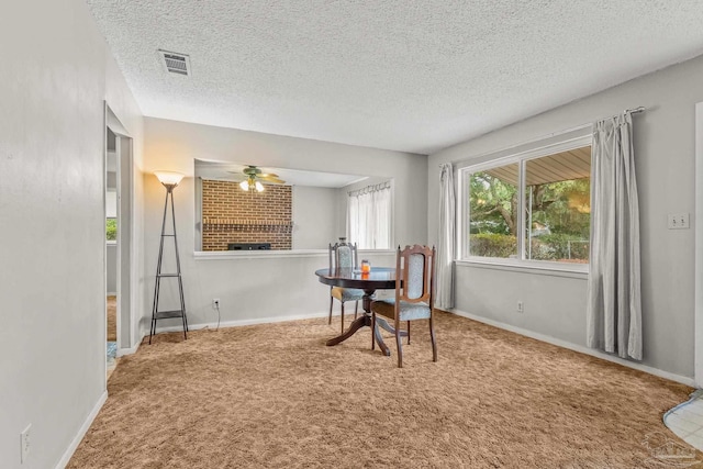 dining area with ceiling fan, carpet floors, a textured ceiling, and a fireplace