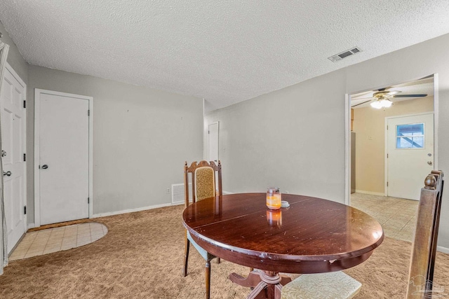 dining room with light carpet, ceiling fan, and a textured ceiling