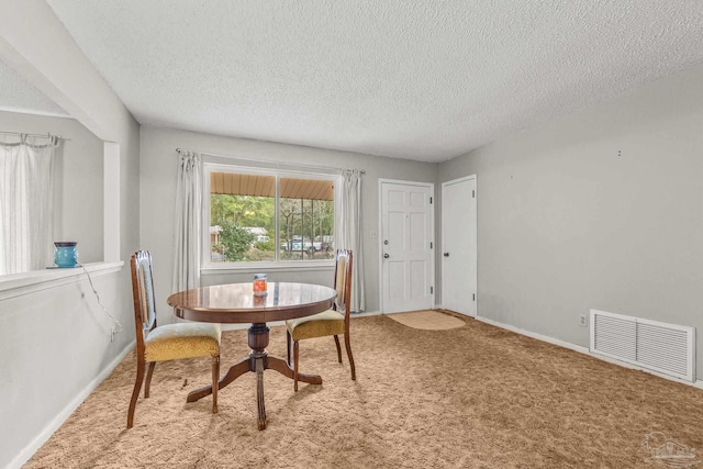 carpeted dining space featuring a textured ceiling