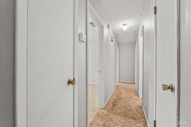 hall with light carpet and a textured ceiling