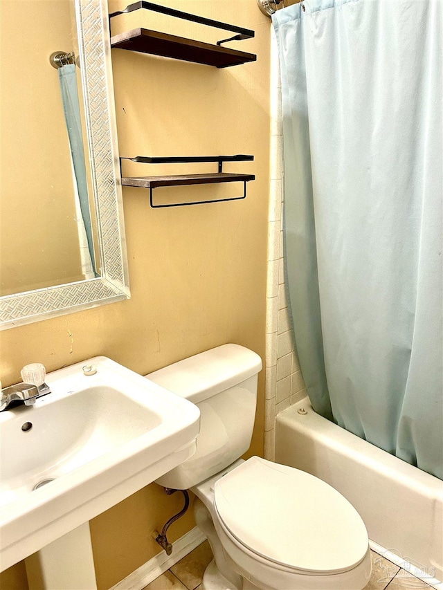 bathroom featuring toilet, tile patterned flooring, shower / bath combo with shower curtain, and a sink