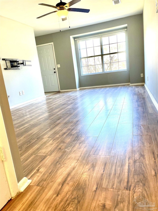 unfurnished room featuring ceiling fan, visible vents, baseboards, and wood finished floors