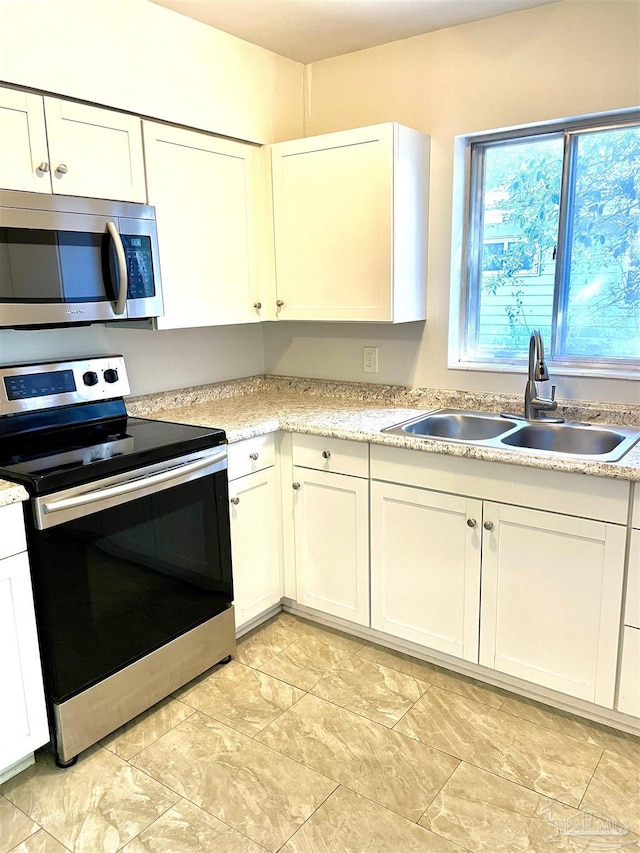 kitchen featuring light countertops, appliances with stainless steel finishes, a sink, and white cabinets